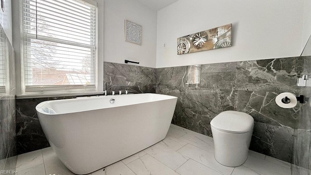 128 Wellons St, Suffolk, VA 23434 - bathroom featuring tile walls, marble finish floors, a soaking tub, toilet, and wainscoting
