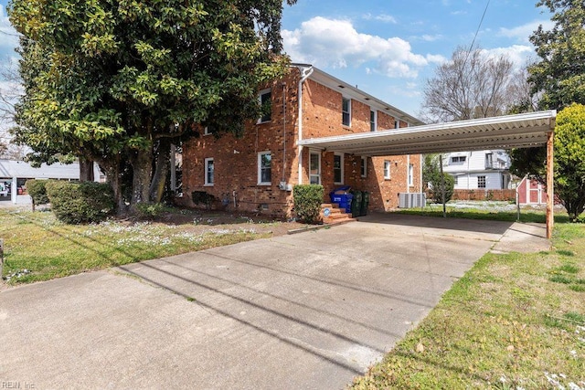 128 Wellons St, Suffolk, VA 23434 - view of front of house with brick siding, a carport, driveway, a front yard, and an outbuilding