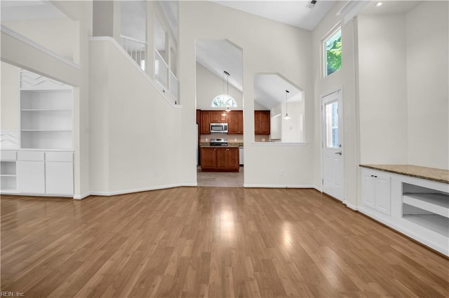 1300 Equinox Lndg, Chesapeake, VA 23322 - unfurnished living room with high vaulted ceiling, light wood-style floors, built in shelves, and baseboards