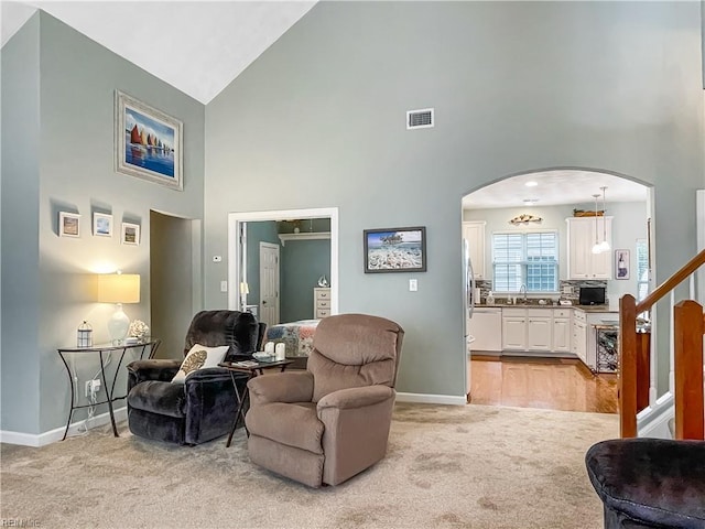 2884 Einstein Dr, Virginia Beach, VA 23456 - living area featuring high vaulted ceiling, light colored carpet, arched walkways, baseboards, and stairway