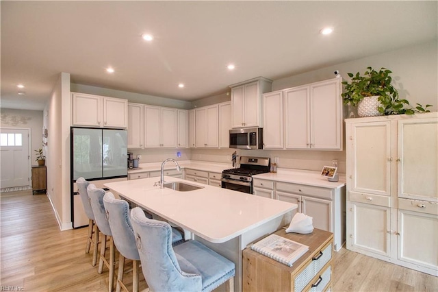 1621 Redwing Arch, Chesapeake, VA 23323 - kitchen featuring appliances with stainless steel finishes, a sink, a center island with sink, light wood finished floors, and a kitchen breakfast bar