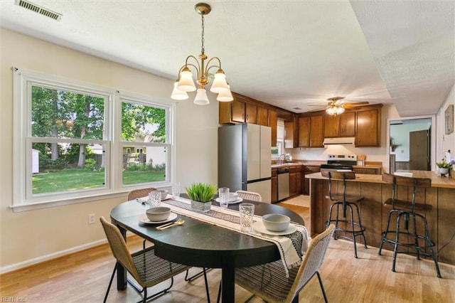 214 Silver Isles Blvd, Hampton, VA 23664 - dining area with light wood-style flooring, a chandelier, baseboards, a textured ceiling, and ceiling fan