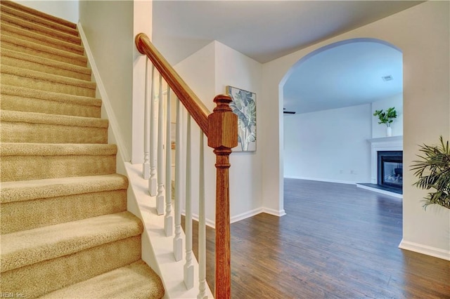 5233 Winery Dr, Chesapeake, VA 23321 - staircase featuring arched walkways, wood finished floors, baseboards, and a glass covered fireplace
