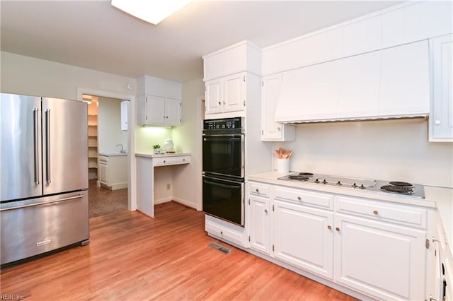 5209 Studeley Ave, Norfolk, VA 23508 - kitchen with freestanding refrigerator, electric stovetop, light countertops, white cabinetry, and light wood finished floors