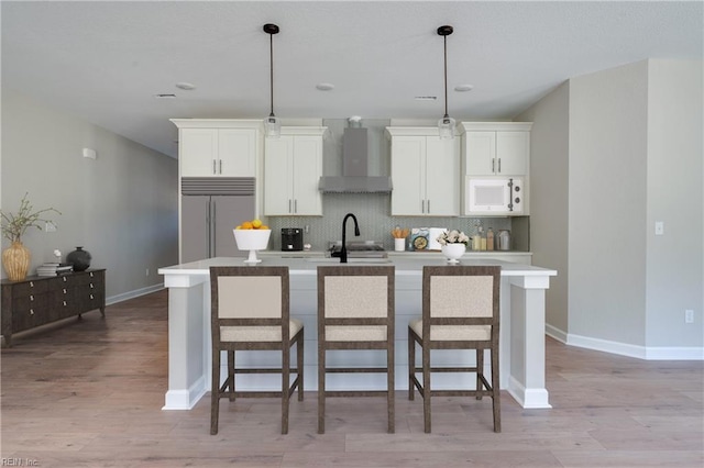 23041 Calvin Dr, Franklin, VA 23851 - kitchen with wall chimney range hood, built in refrigerator, white microwave, a center island with sink, and backsplash