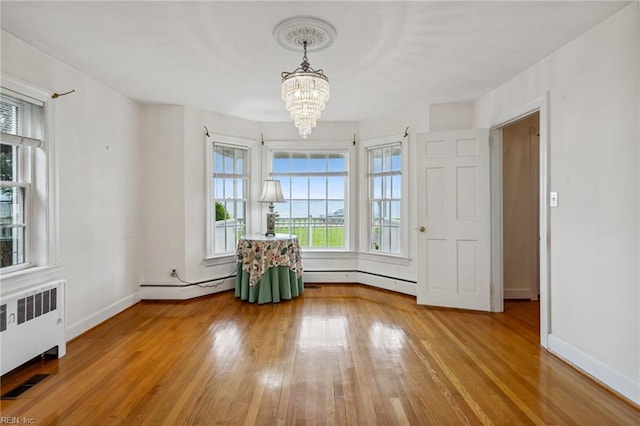 3403 Chesapeake Ave, Hampton, VA 23661 - unfurnished room with radiator heating unit, a baseboard radiator, a chandelier, wood-type flooring, and baseboards