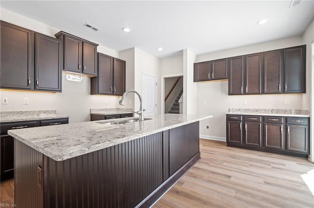 2300 Venture Way Unit B, Suffolk, VA 23434 - kitchen featuring a sink, light wood-type flooring, dark brown cabinetry, light stone counters, and a kitchen island with sink