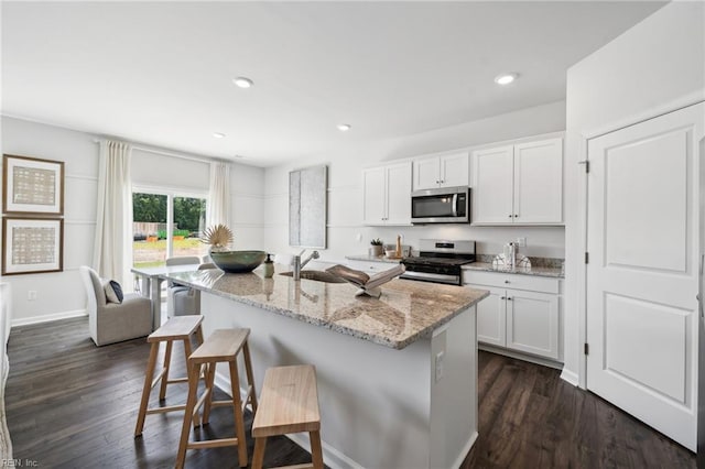 3031 Dalton Cir, Suffolk, VA 23435 - kitchen with stainless steel appliances, a breakfast bar area, light stone countertops, white cabinets, and dark wood finished floors