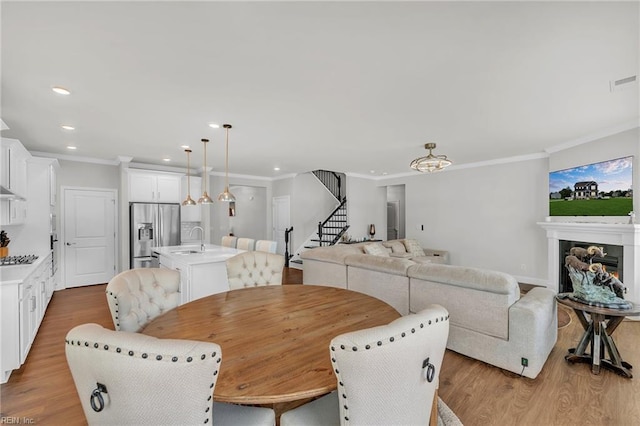 3001 Brylie Ct, Suffolk, VA 23435 - dining area featuring stairs, wood finished floors, recessed lighting, crown molding, and a warm lit fireplace