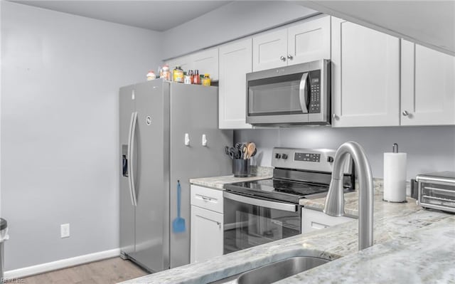 403 Joel Ct, Newport News, VA 23608 - kitchen with appliances with stainless steel finishes, light stone counters, white cabinets, a sink, and light wood finished floors
