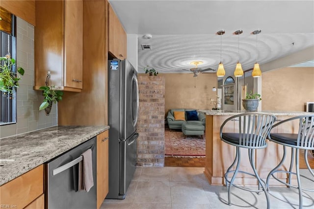 224 Iroquois Rd, Virginia Beach, VA 23462 - kitchen with stainless steel appliances, brown cabinets, a breakfast bar, light stone countertops, and hanging light fixtures