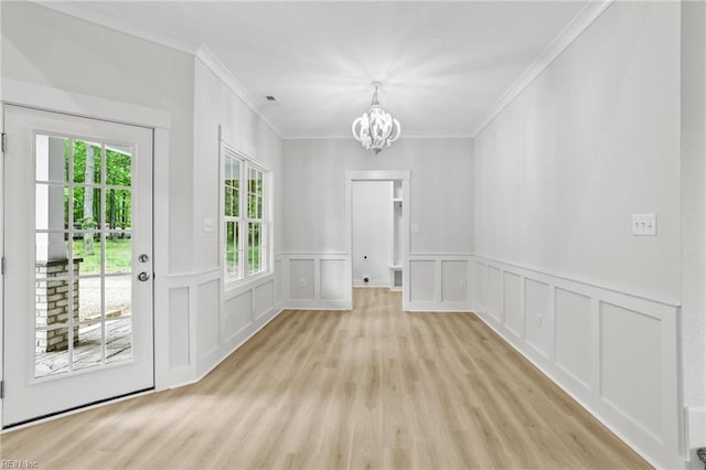 1064 Tulls Creek Rd, Moyock, NC 27958 - unfurnished dining area with plenty of natural light, a chandelier, crown molding, light wood-style floors, and a decorative wall