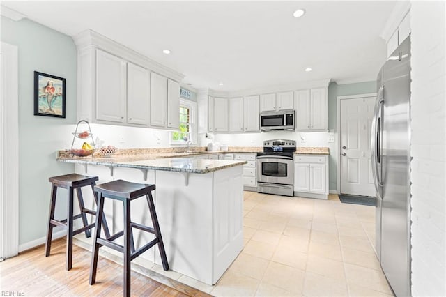1808 Ashley Dr, Virginia Beach, VA 23454 - kitchen featuring stainless steel appliances, a peninsula, a sink, white cabinetry, and light stone counters