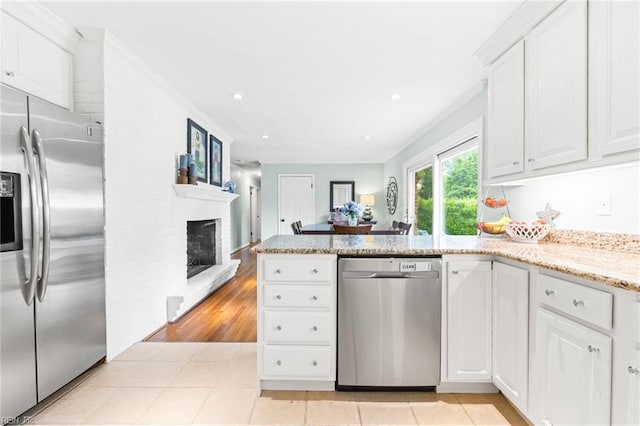 1808 Ashley Dr, Virginia Beach, VA 23454 - kitchen with stainless steel appliances, a peninsula, a brick fireplace, white cabinetry, and ornamental molding