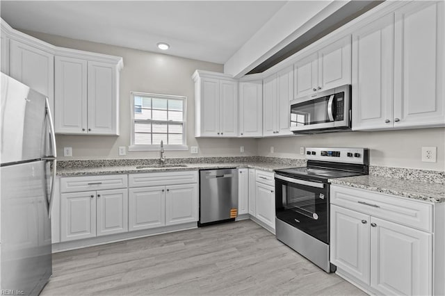 2905 Roanoke Ave, Newport News, VA 23607 - kitchen with appliances with stainless steel finishes, a sink, white cabinetry, light wood-type flooring, and light stone countertops