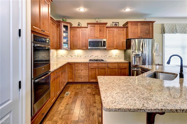 3907 Ethan Ln, Williamsburg, VA 23188 - kitchen with appliances with stainless steel finishes, a sink, dark wood finished floors, brown cabinetry, and glass insert cabinets