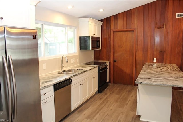 5857 Frament Ave, Norfolk, VA 23502 - kitchen with stainless steel appliances, a sink, light wood-style flooring, wooden walls, and white cabinets