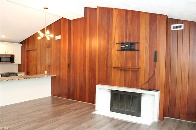 5857 Frament Ave, Norfolk, VA 23502 - unfurnished living room featuring wooden walls, a fireplace, a chandelier, wood finished floors, and vaulted ceiling