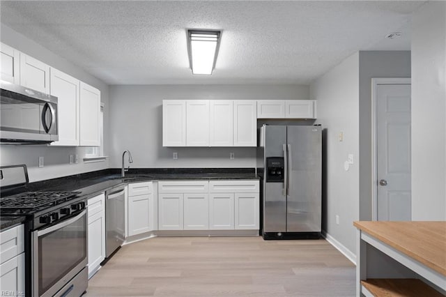 6218 Whaley Ct, Norfolk, VA 23502 - kitchen with stainless steel appliances, a sink, light wood-type flooring, white cabinets, and a textured ceiling