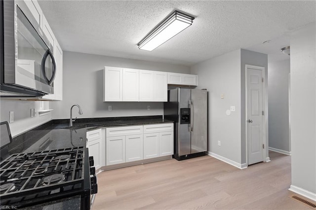 6218 Whaley Ct, Norfolk, VA 23502 - kitchen featuring appliances with stainless steel finishes, a sink, light wood-style floors, a textured ceiling, and white cabinets