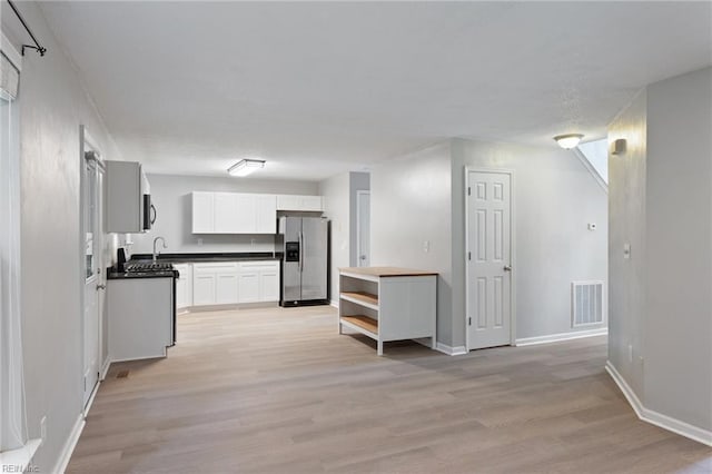 6218 Whaley Ct, Norfolk, VA 23502 - kitchen with appliances with stainless steel finishes, dark countertops, light wood-style floors, white cabinets, and baseboards