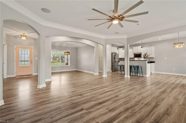 1120 Veranda Way, Chesapeake, VA 23320 - unfurnished living room featuring wood finished floors, ornamental molding, baseboards, a ceiling fan, and arched walkways