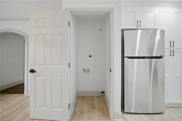 8715 Semmes Ave, Norfolk, VA 23503 - kitchen with freestanding refrigerator, light wood-type flooring, white cabinetry, arched walkways, and baseboards