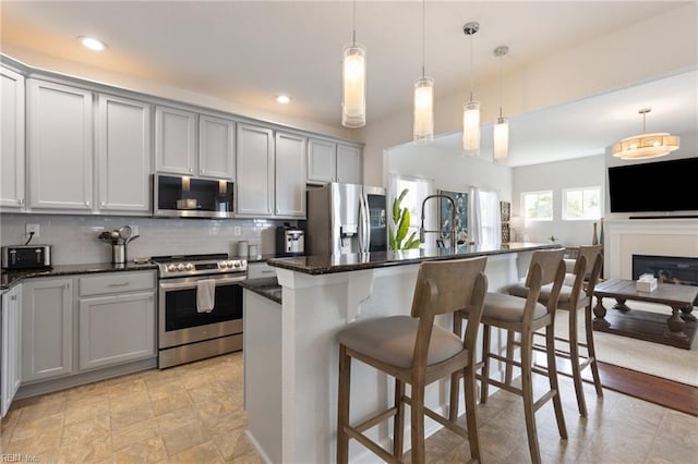 1025 Sullivan Ln, Chesapeake, VA 23322 - kitchen with appliances with stainless steel finishes, gray cabinetry, tasteful backsplash, a breakfast bar, and a kitchen island with sink