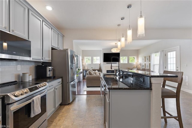 1025 Sullivan Ln, Chesapeake, VA 23322 - kitchen featuring appliances with stainless steel finishes, open floor plan, gray cabinetry, a breakfast bar, and tasteful backsplash