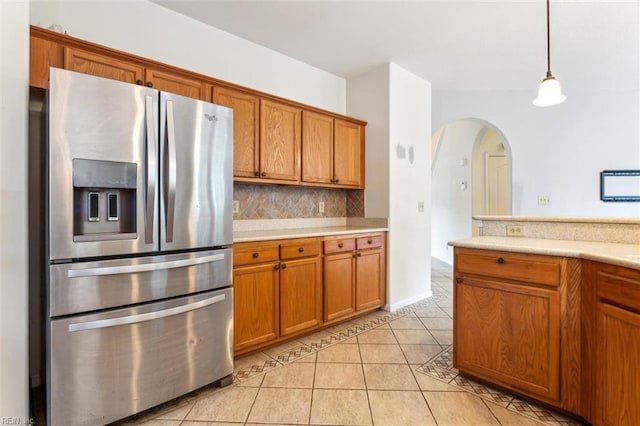 109 Lenora Cv, Smithfield, VA 23430 - kitchen with stainless steel refrigerator with ice dispenser, brown cabinetry, light tile patterned floors, light countertops, and arched walkways