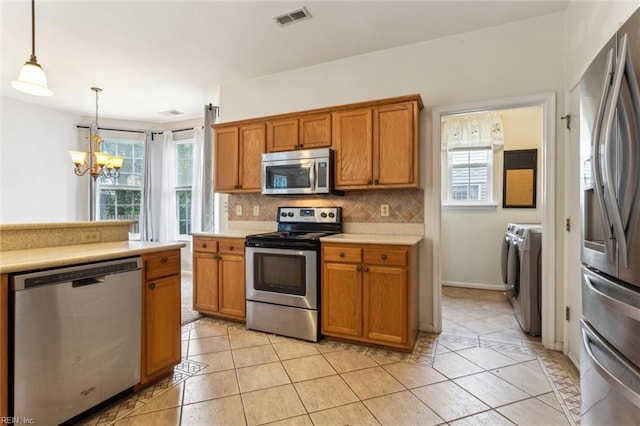 109 Lenora Cv, Smithfield, VA 23430 - kitchen with appliances with stainless steel finishes, independent washer and dryer, brown cabinetry, and a chandelier