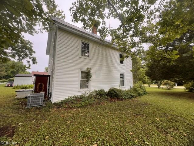 1717 Old Ferry Rd, Hudgins, VA 23076 - view of property exterior featuring a lawn, a chimney, and central AC