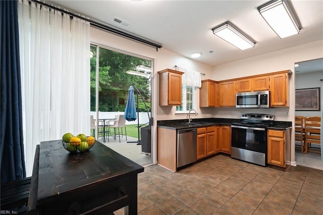 302 Peachwood Ct, Suffolk, VA 23434 - kitchen with stainless steel appliances, a sink, dark countertops, and brown cabinetry