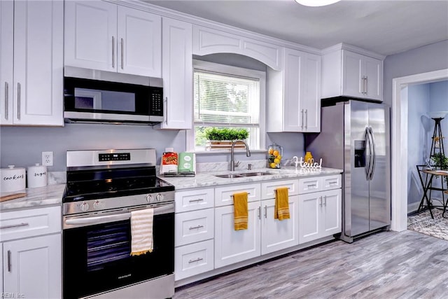 319 Greenbriar Ave, Hampton, VA 23661 - kitchen featuring appliances with stainless steel finishes, a sink, white cabinetry, light wood-style floors, and light stone countertops