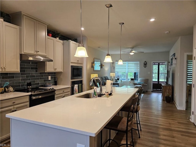 23082 Retreat Ln, Carrollton, VA 23314 - kitchen with electric stove, under cabinet range hood, a sink, built in microwave, and open floor plan