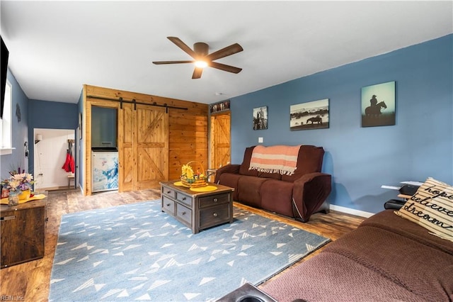891 Bells Mill Rd, Chesapeake, VA 23322 - living room with a barn door, a ceiling fan, wood finished floors, wooden walls, and baseboards