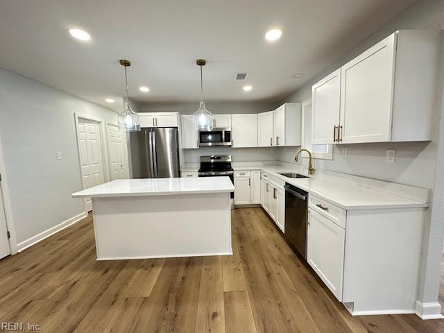 128 Ridgewood Rd, Chesapeake, VA 23325 - kitchen with stainless steel appliances, a sink, white cabinets, a kitchen island, and wood finished floors