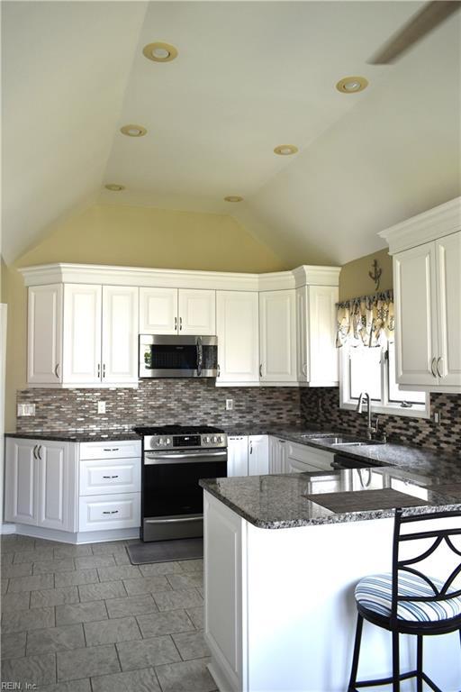 1176 Pond Cypress Dr, Virginia Beach, VA 23455 - kitchen featuring stainless steel appliances, a sink, vaulted ceiling, white cabinets, and tasteful backsplash