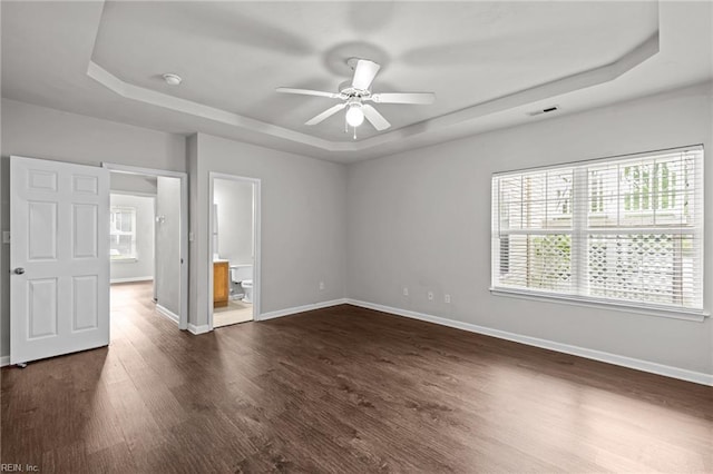 408 Coastal Walk Pl Unit 102, Virginia Beach, VA 23451 - unfurnished bedroom featuring a tray ceiling, multiple windows, baseboards, and dark wood-style flooring