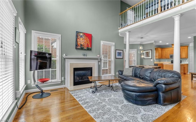 106 Edith Wharton Sq, Newport News, VA 23606 - living room with ornate columns, a towering ceiling, a fireplace with flush hearth, wood finished floors, and baseboards
