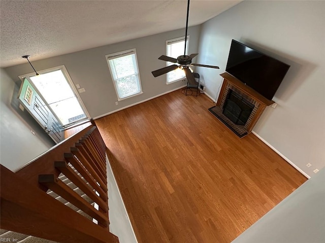 2304 Londale Ct, Virginia Beach, VA 23456 - unfurnished living room with ceiling fan, wood finished floors, a brick fireplace, baseboards, and a textured ceiling