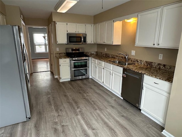 2304 Londale Ct, Virginia Beach, VA 23456 - kitchen featuring appliances with stainless steel finishes, a sink, wood finished floors, white cabinets, and dark stone counters
