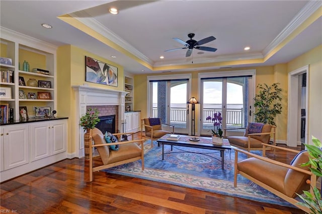 509 River Blfs, Williamsburg, VA 23185 - living room featuring a raised ceiling, crown molding, ceiling fan, a tiled fireplace, and dark wood-type flooring