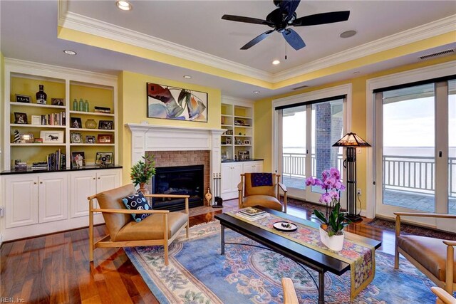 509 River Blfs, Williamsburg, VA 23185 - living area featuring dark wood-style flooring, a ceiling fan, a fireplace with flush hearth, ornamental molding, and a tray ceiling