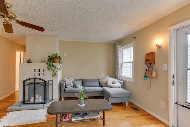 428 Macdonald Cres, Norfolk, VA 23505 - living room featuring light wood-type flooring, a fireplace, a textured ceiling, ceiling fan, and baseboards