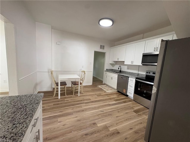 3711 Abingdon Cir, Norfolk, VA 23513 - kitchen with appliances with stainless steel finishes, a sink, white cabinetry, dark stone counters, and light wood-style floors