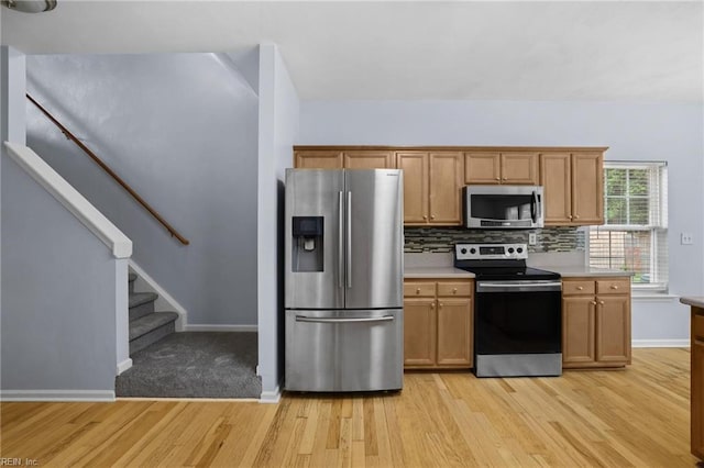 2110 King St, Suffolk, VA 23434 - kitchen with stainless steel appliances, light wood finished floors, baseboards, backsplash, and light countertops