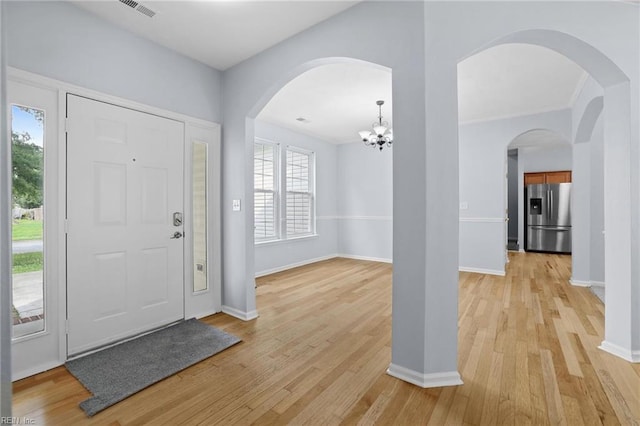 2110 King St, Suffolk, VA 23434 - foyer entrance featuring light wood finished floors, a chandelier, baseboards, and arched walkways