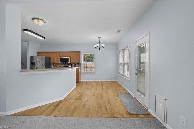 2110 King St, Suffolk, VA 23434 - kitchen featuring stainless steel appliances, a chandelier, brown cabinetry, baseboards, and light wood finished floors