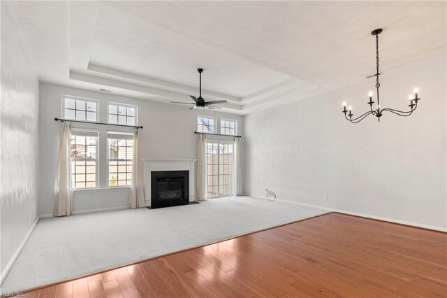 310 Lighthouse Way, Carrollton, VA 23314 - unfurnished living room with wood-type flooring, a raised ceiling, baseboards, a chandelier, and a ceiling fan